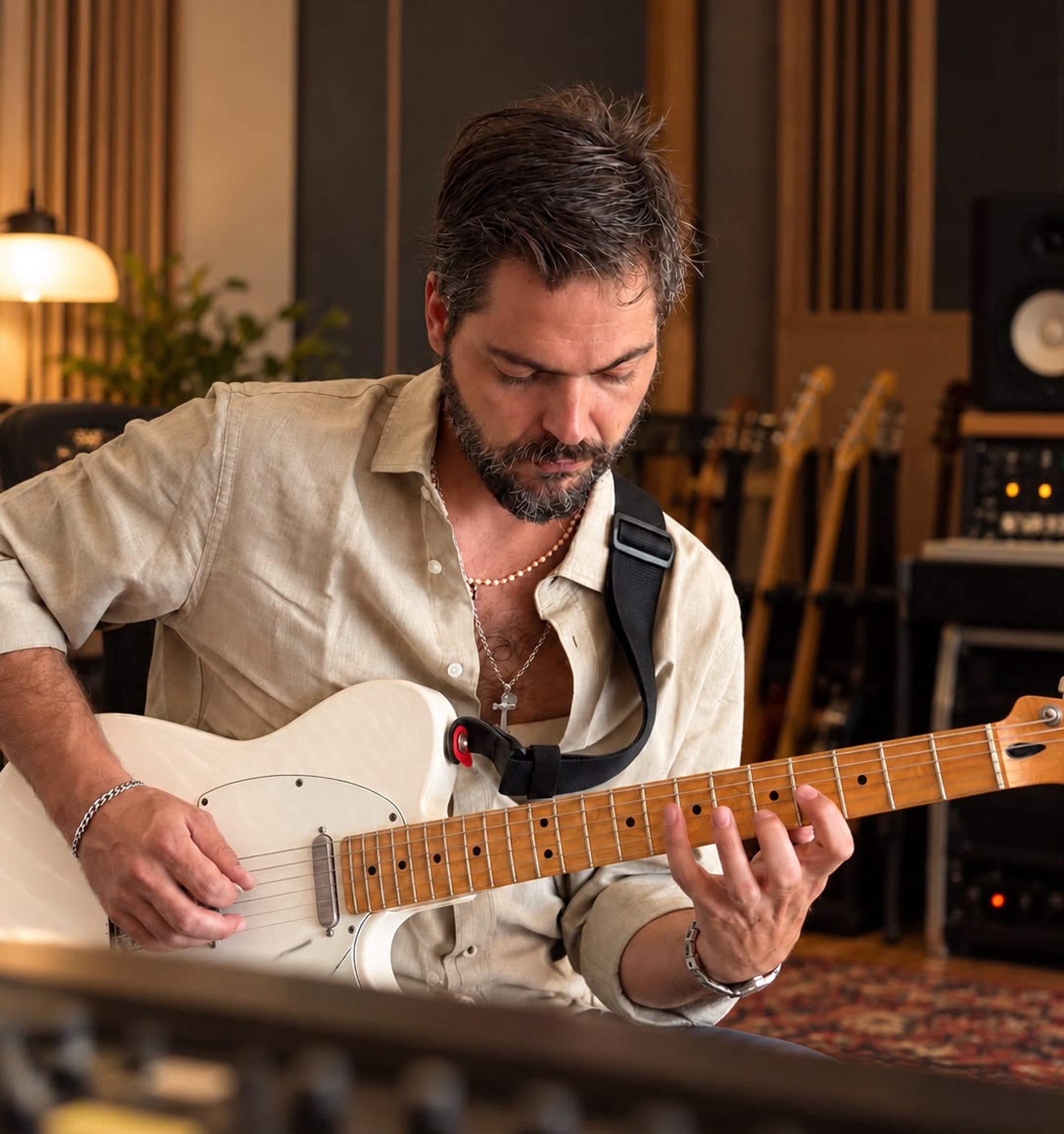 António Roque playing a white electric guitar in a recording studio